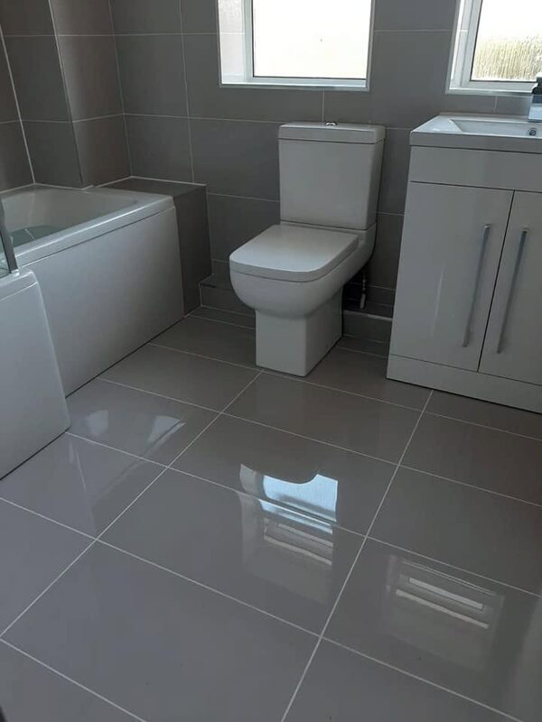 Bath, toilet and white vanity unit on a large-format gloss tiled floor