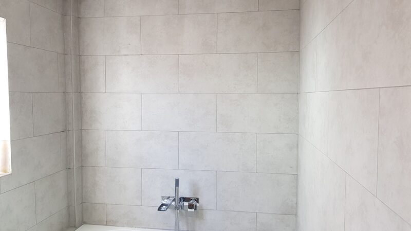 Light grey tiled shower wall with a concealed mixer valve set into it
